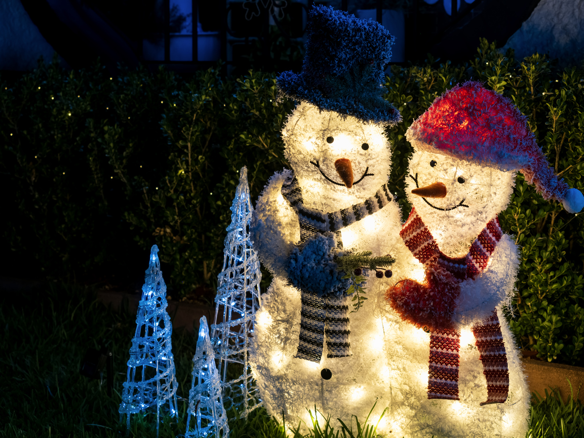 Two side-by-side effigies of illuminated Christmas Snowmen with festive decorative lights